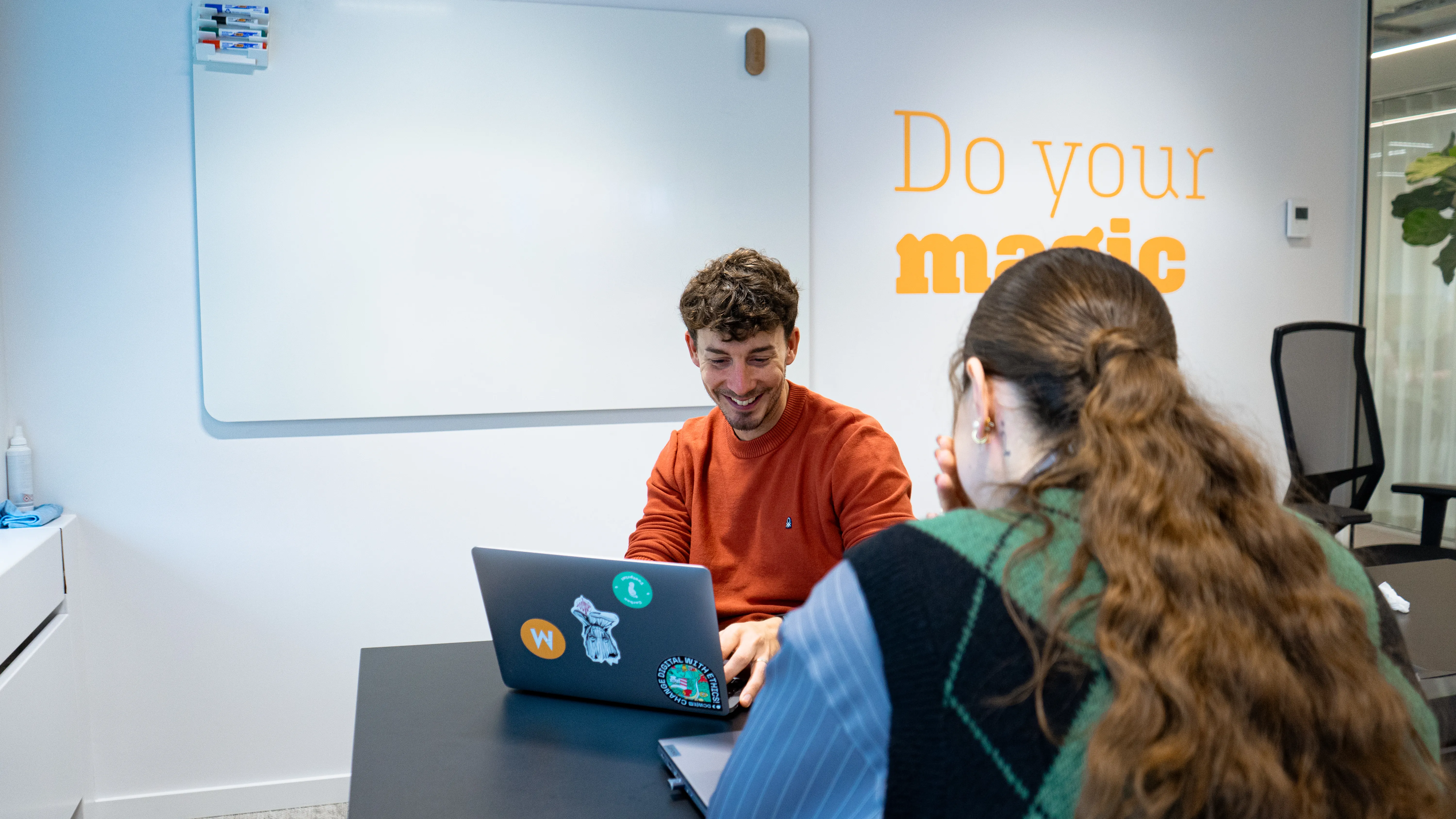 Two colleagues working on a laptop in a modern office