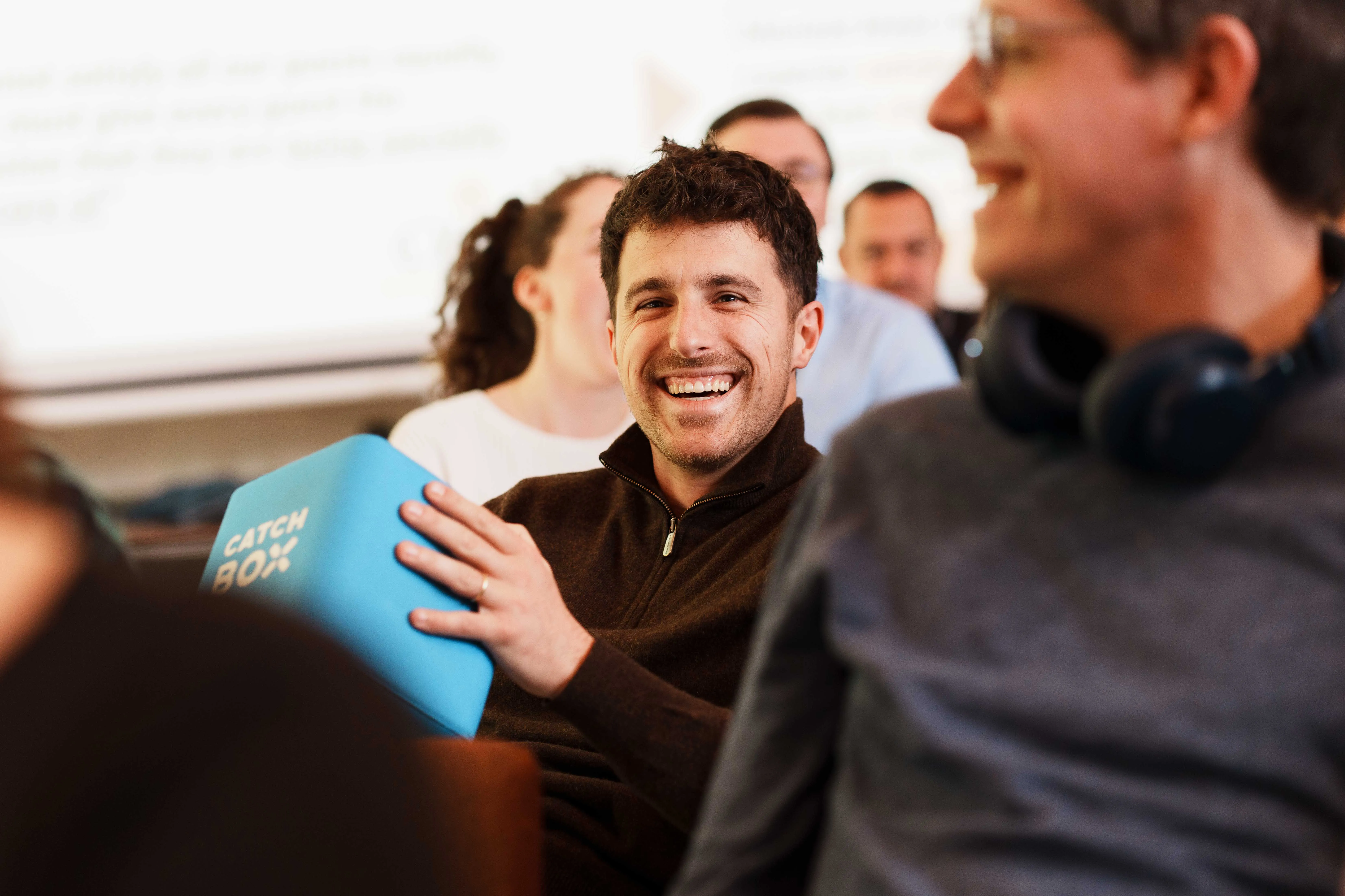 Four diverse colleagues walking and laughing in an office hallway