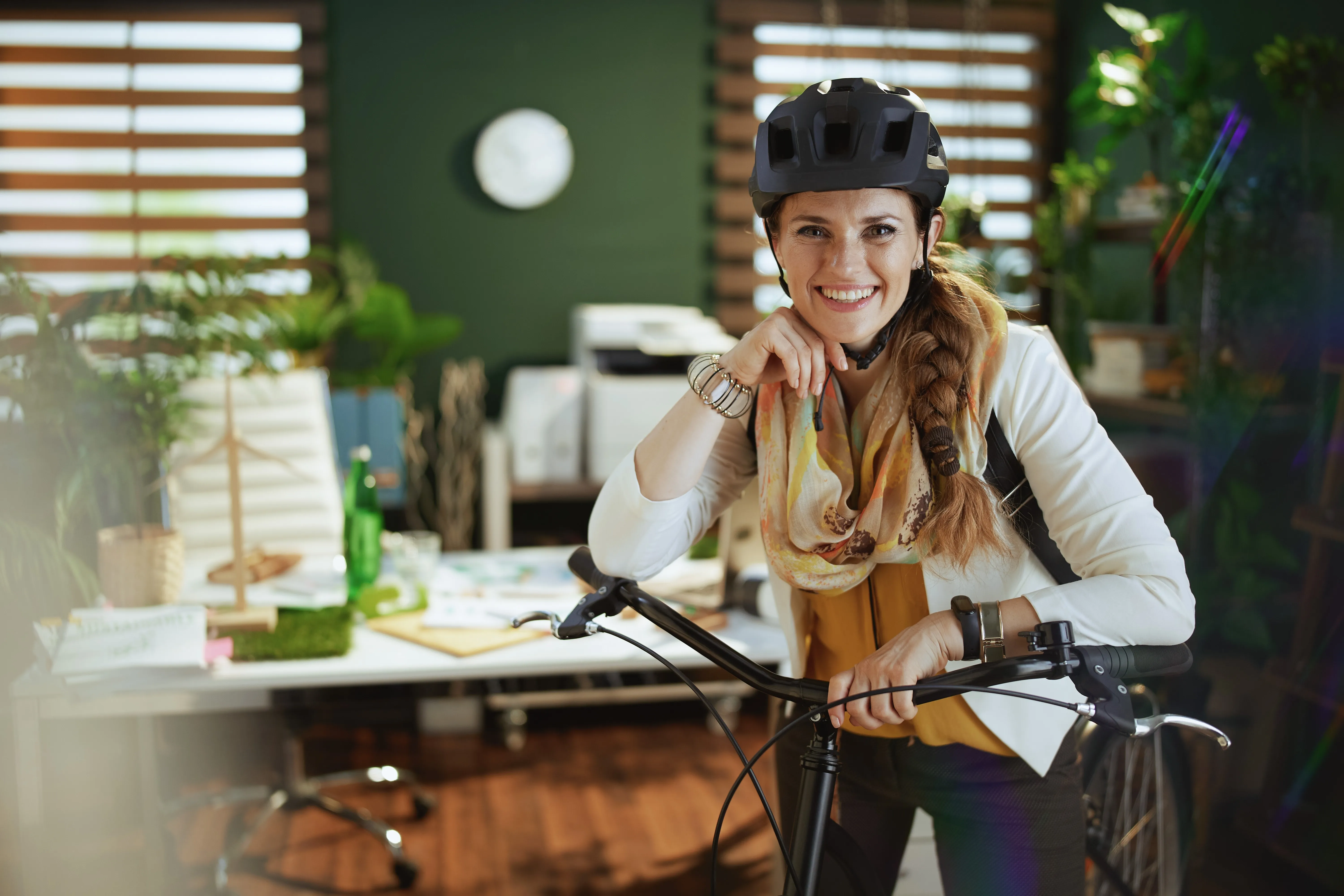 Smiling woman with bicycle at the office -- eco mobility